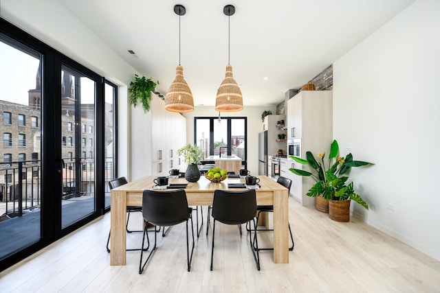 dining room featuring french doors, light wood-type flooring, and baseboards