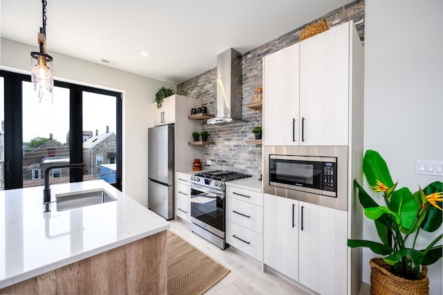 kitchen with decorative backsplash, open shelves, a sink, stainless steel appliances, and wall chimney exhaust hood