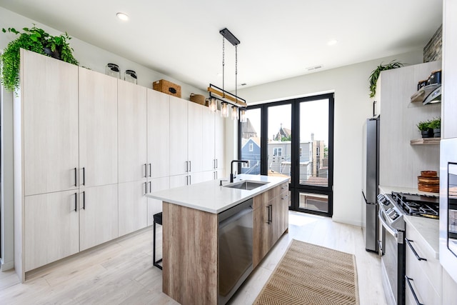 kitchen featuring modern cabinets, a sink, stainless steel appliances, visible vents, and an island with sink