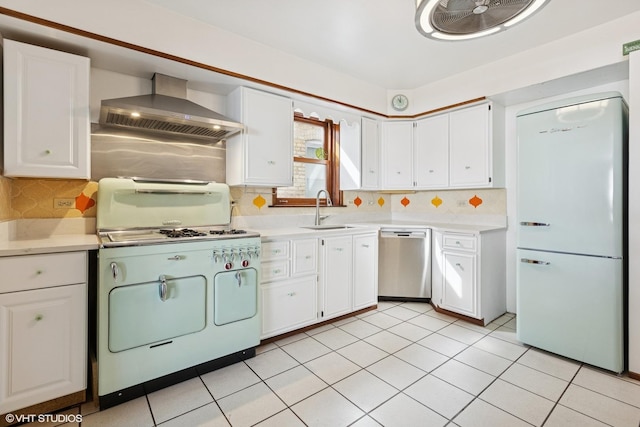 kitchen featuring light countertops, a sink, white appliances, wall chimney exhaust hood, and white cabinetry