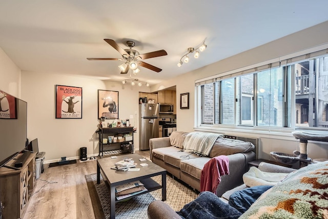 living room featuring baseboards, a ceiling fan, light wood-type flooring, and rail lighting