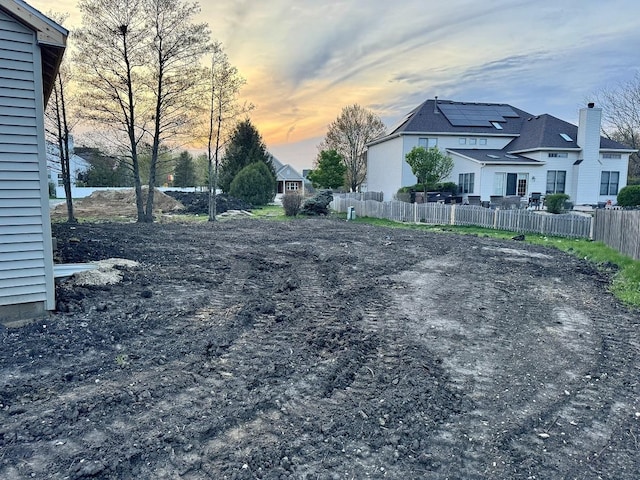 yard at dusk featuring fence and a residential view