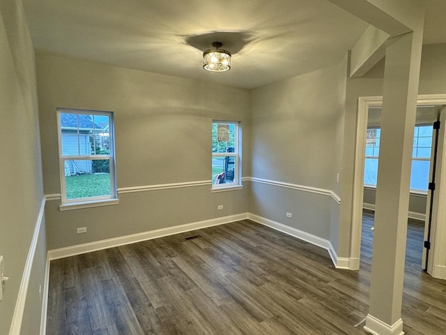 spare room with dark wood finished floors, baseboards, and a healthy amount of sunlight