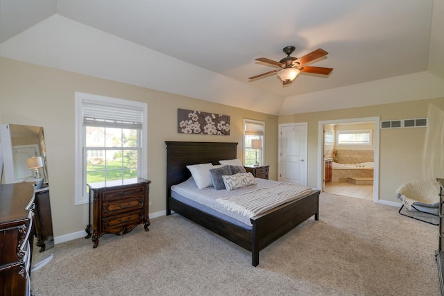 bedroom featuring light carpet, ensuite bath, vaulted ceiling, ceiling fan, and baseboards