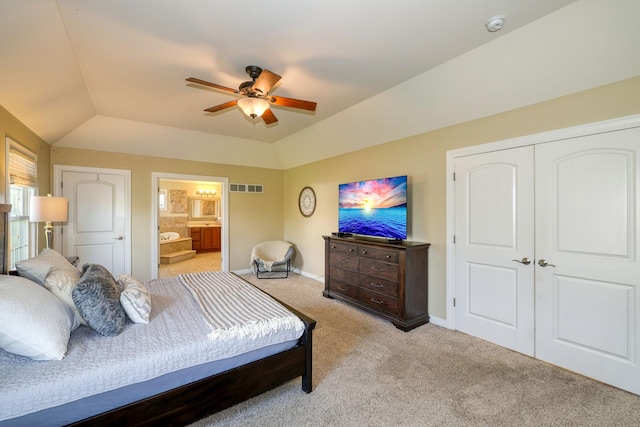 bedroom featuring lofted ceiling, light carpet, baseboards, ensuite bathroom, and ceiling fan