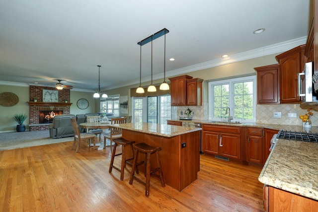 kitchen with a sink, open floor plan, appliances with stainless steel finishes, light wood-style floors, and crown molding