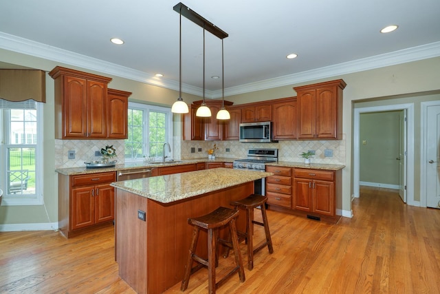 kitchen featuring a sink, stainless steel appliances, a kitchen island, a kitchen breakfast bar, and decorative light fixtures