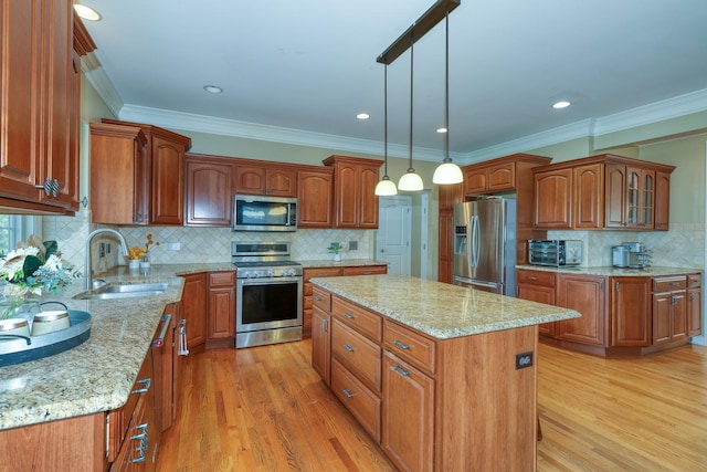 kitchen featuring stainless steel appliances, a sink, a center island, light wood-style flooring, and ornamental molding