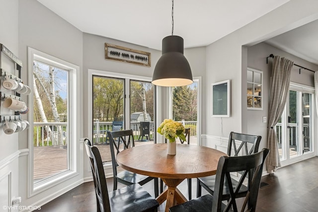 dining room featuring a wainscoted wall and dark wood-style flooring