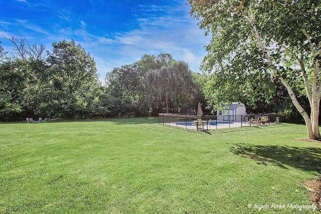view of yard featuring a fenced in pool, fence, an outbuilding, and a shed