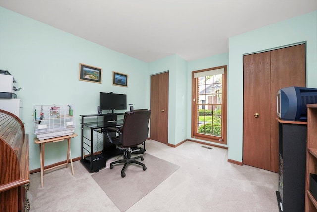 office area featuring baseboards, visible vents, and light colored carpet