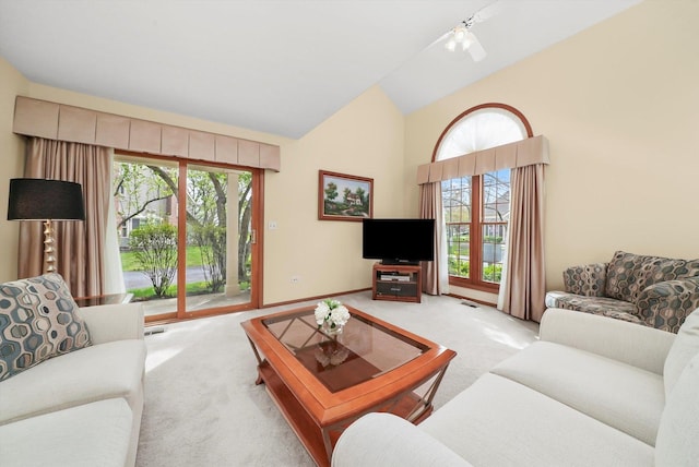 carpeted living room with a healthy amount of sunlight, high vaulted ceiling, baseboards, and visible vents