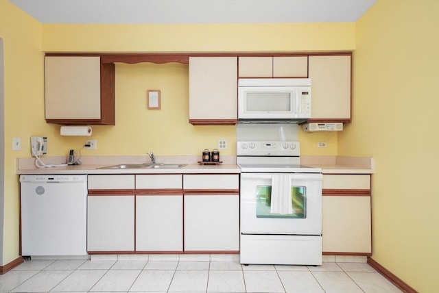 kitchen with white appliances, baseboards, a sink, and light countertops