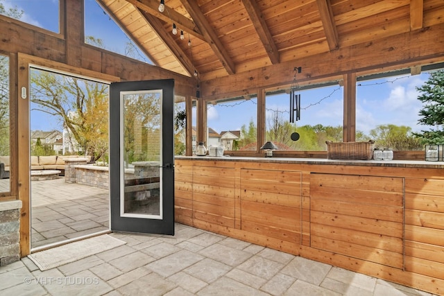 sunroom featuring stone tile floors, wood walls, lofted ceiling with beams, and wood ceiling