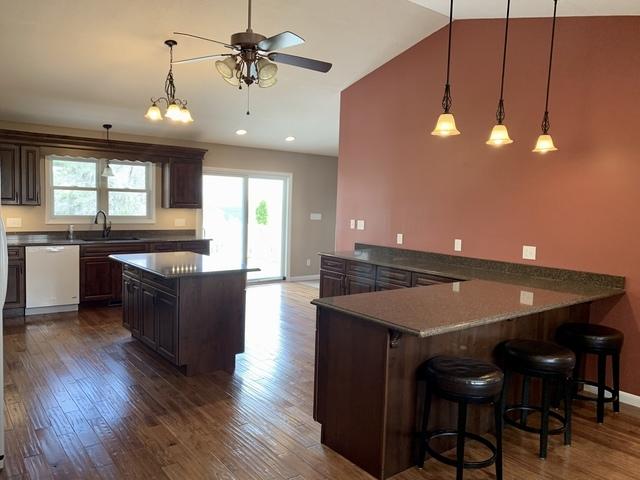 2700 E 600 N Rd, Milford, IL 60953 - kitchen with dark wood-style flooring, a breakfast bar, ceiling fan, a sink, and dishwashing machine