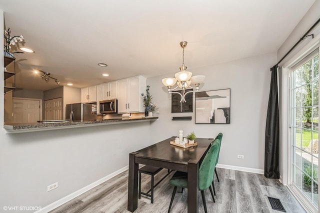 3095 Courtland St Unit 0, Woodstock, IL 60098 - dining space featuring baseboards, wood finished floors, a notable chandelier, and visible vents
