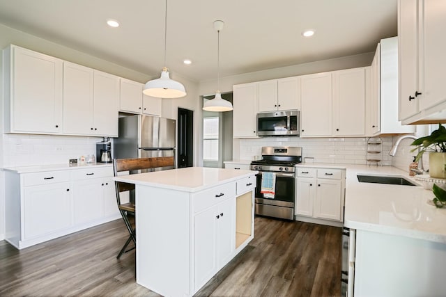 9303 Enstrom Ln, Huntley, IL 60142 - kitchen featuring appliances with stainless steel finishes, a center island, tasteful backsplash, white cabinetry, and dark wood-style flooring