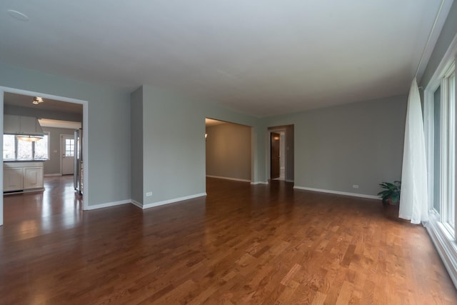 spare room featuring baseboards and dark wood-style floors