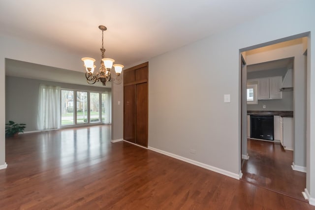 empty room featuring baseboards, a notable chandelier, and dark wood-style floors