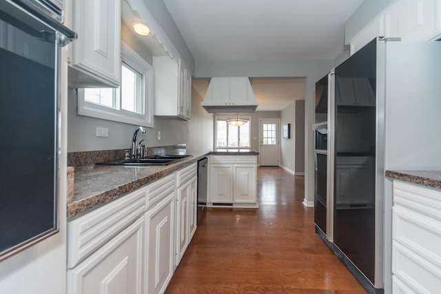 kitchen with high end fridge, a sink, dishwasher, dark wood finished floors, and white cabinetry