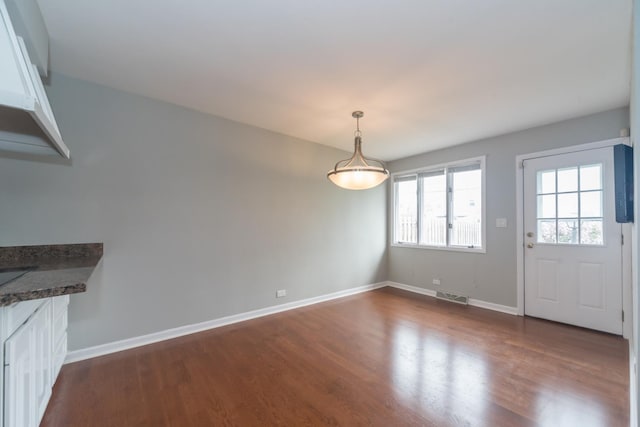 unfurnished dining area with dark wood finished floors, visible vents, and baseboards