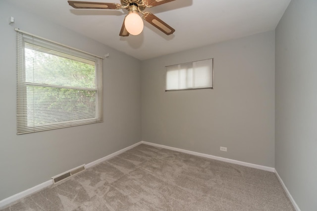 empty room with ceiling fan, light carpet, visible vents, and baseboards