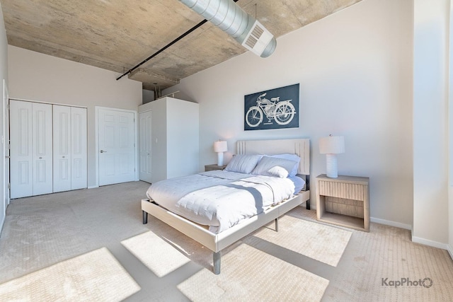 carpeted bedroom featuring baseboards and two closets