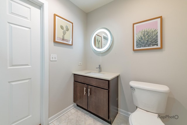 bathroom featuring marble finish floor, baseboards, toilet, and vanity