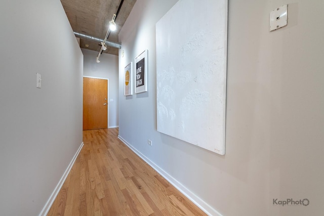 hall featuring rail lighting, baseboards, and wood finished floors