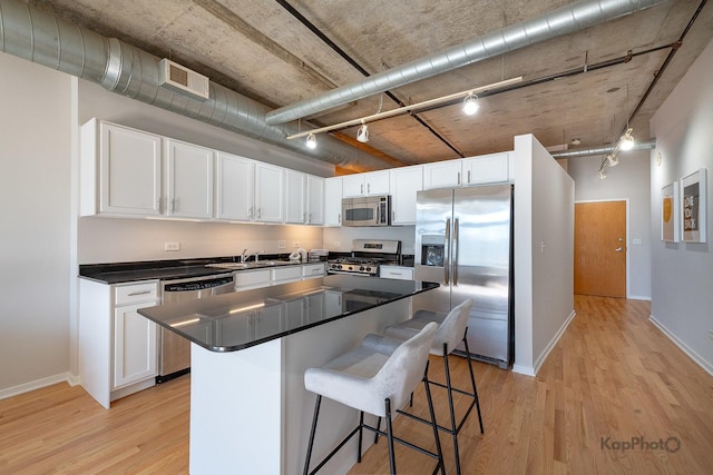 kitchen featuring rail lighting, stainless steel appliances, visible vents, and a sink