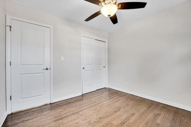 unfurnished bedroom with wood finished floors, a closet, a ceiling fan, and baseboards