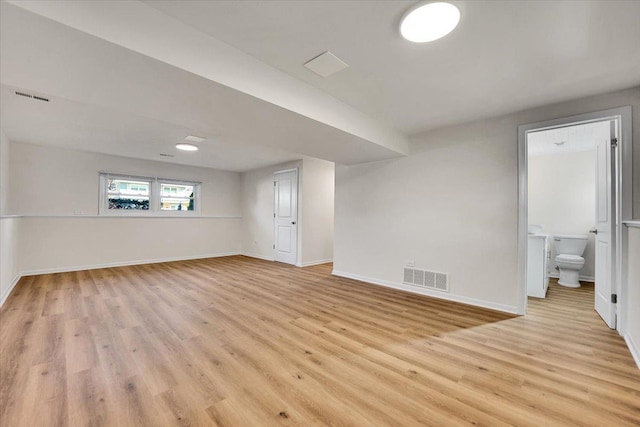 below grade area featuring baseboards, light wood finished floors, and visible vents