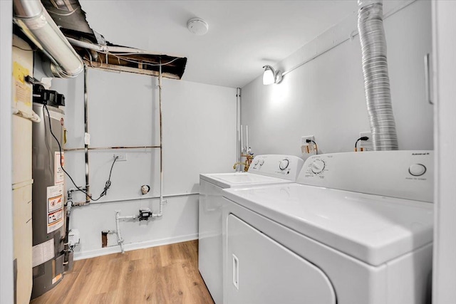 laundry area with light wood-type flooring, water heater, baseboards, and washer and dryer