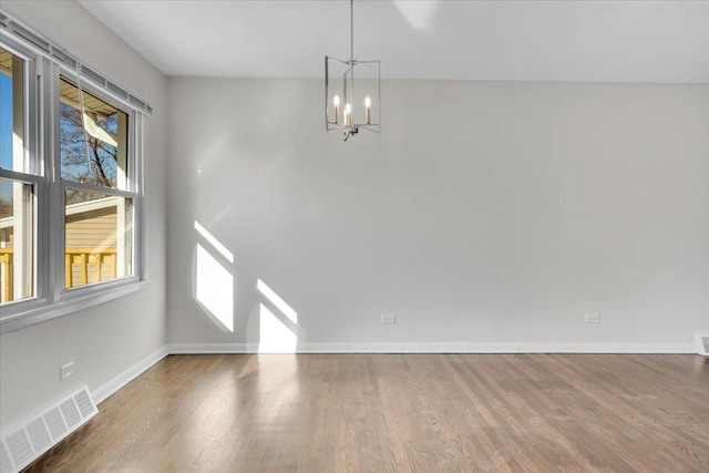 unfurnished dining area featuring baseboards, visible vents, a wealth of natural light, and a notable chandelier