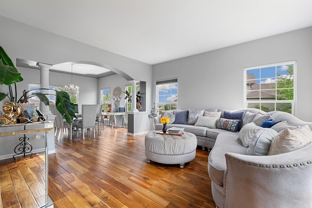 living room featuring arched walkways, decorative columns, a chandelier, and hardwood / wood-style floors
