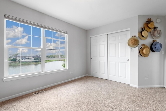 unfurnished bedroom featuring carpet floors, baseboards, visible vents, and a closet
