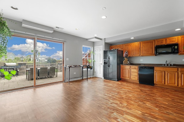kitchen with visible vents, a sink, black appliances, and light wood-type flooring