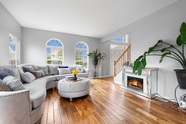 living room featuring a healthy amount of sunlight, stairs, and hardwood / wood-style floors