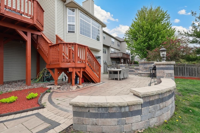 back of property with a wooden deck, a patio, a chimney, and stairs