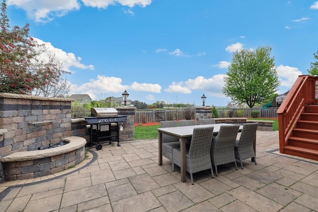 view of patio featuring a fenced backyard, outdoor dining space, stairs, and area for grilling
