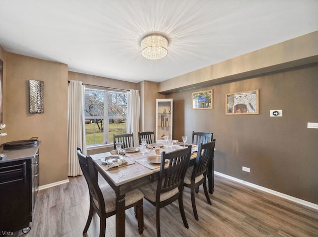 dining area featuring a notable chandelier, wood finished floors, and baseboards