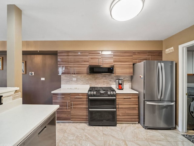 kitchen featuring stainless steel appliances, brown cabinetry, marble finish floor, backsplash, and light countertops
