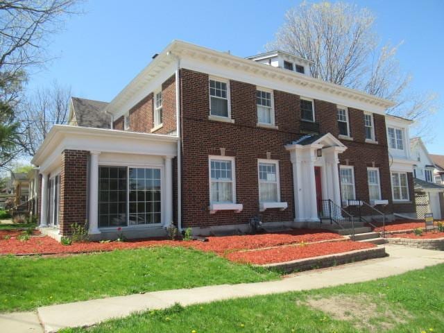 georgian-style home featuring a front yard and brick siding