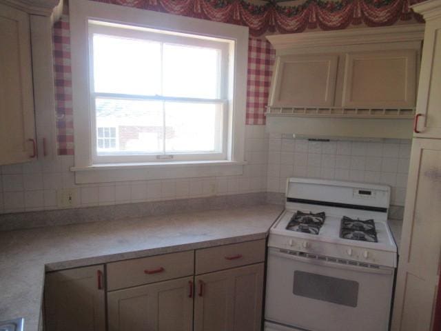 kitchen with light countertops, white gas range oven, and decorative backsplash