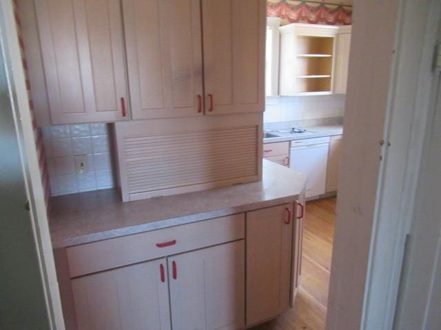 kitchen featuring light countertops, tasteful backsplash, light wood-type flooring, and dishwasher