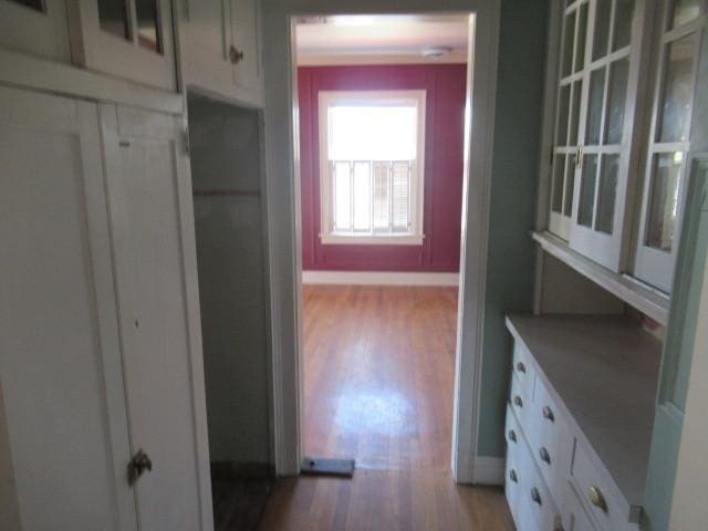 corridor with baseboards and light wood finished floors