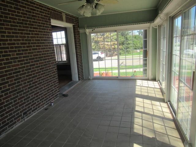 unfurnished sunroom featuring a ceiling fan
