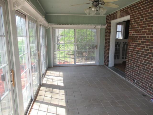 unfurnished sunroom featuring ceiling fan