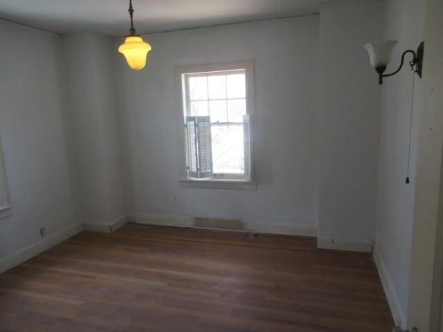 spare room featuring baseboards and wood finished floors