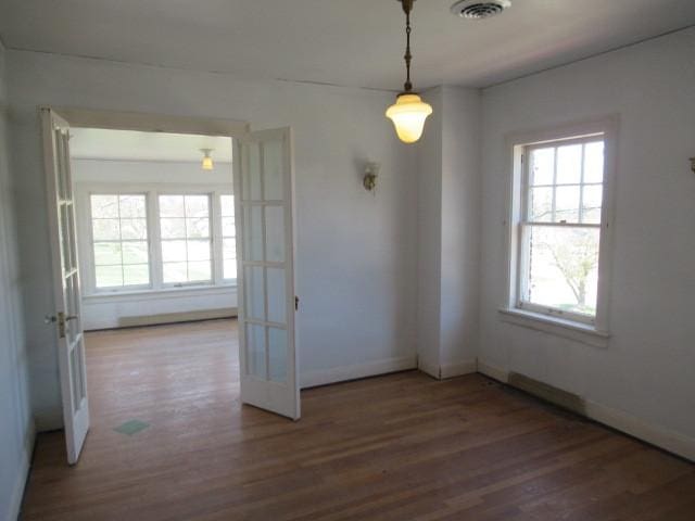 unfurnished dining area with plenty of natural light, wood finished floors, and visible vents